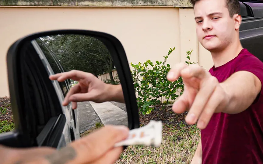 Promotional still from Gay Wire showing a man in a maroon T-shirt outdoors beside a car
