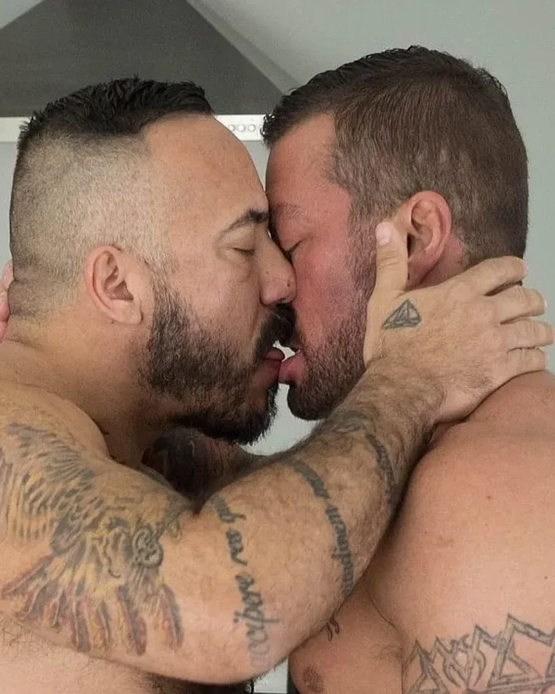 Hairy and Raw stars Alessio Romero and Hugh Hunter, shirtless and tattooed, locked in a deep kiss