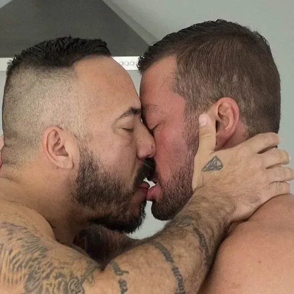 Hairy and Raw stars Alessio Romero and Hugh Hunter, shirtless and tattooed, locked in a deep kiss